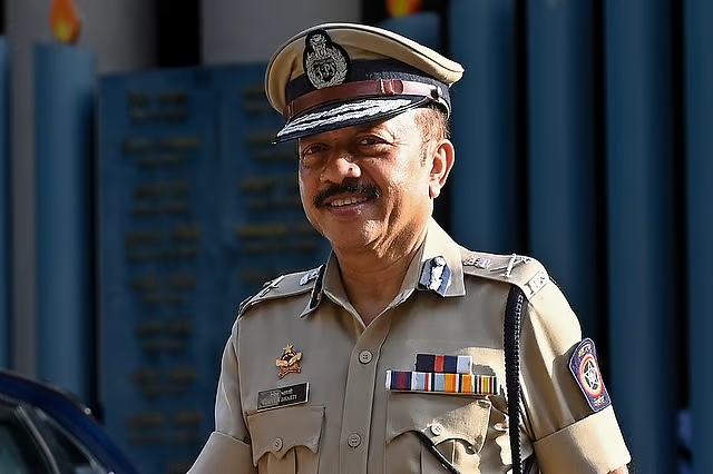 Deven Bharti in Mumbai Police uniform and peaked cap outside a police building.