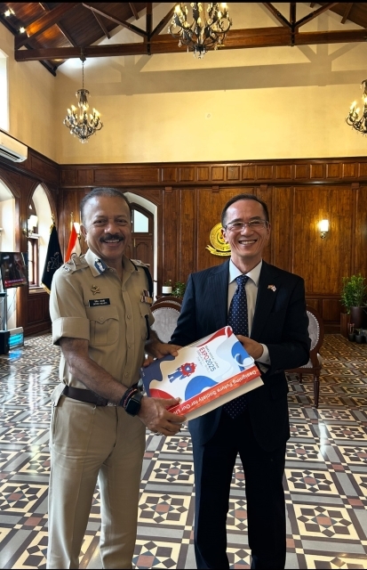 Deven Bharti in uniform receiving a visiting diplomat in the wood-panelled Commissioner's office.