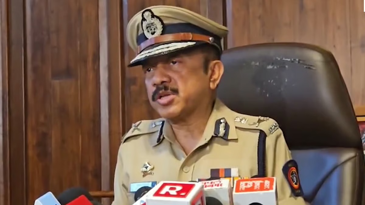 Deven Bharti addressing a press conference in uniform, seated behind a bank of microphones.